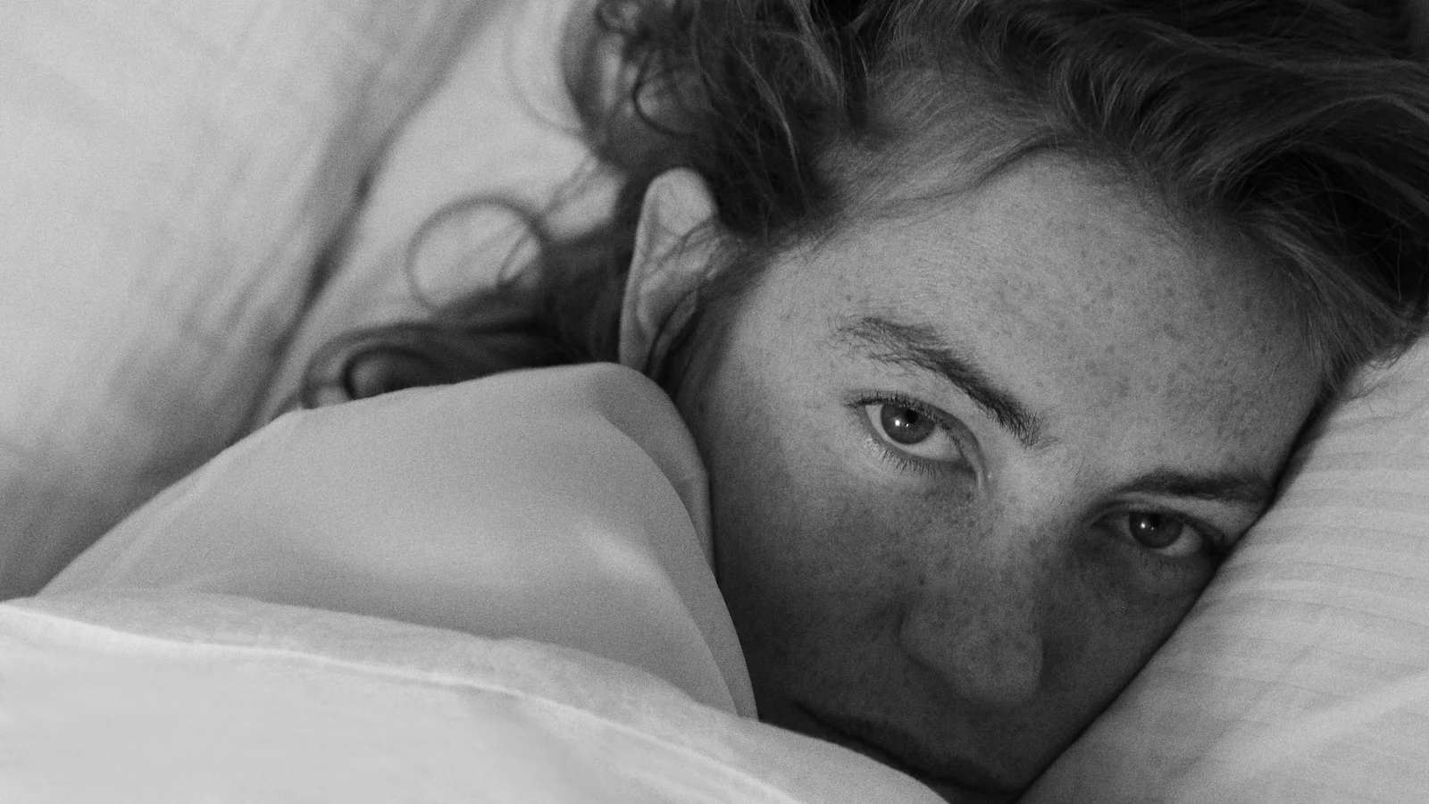 Woman resting in white Beltrami bed linen