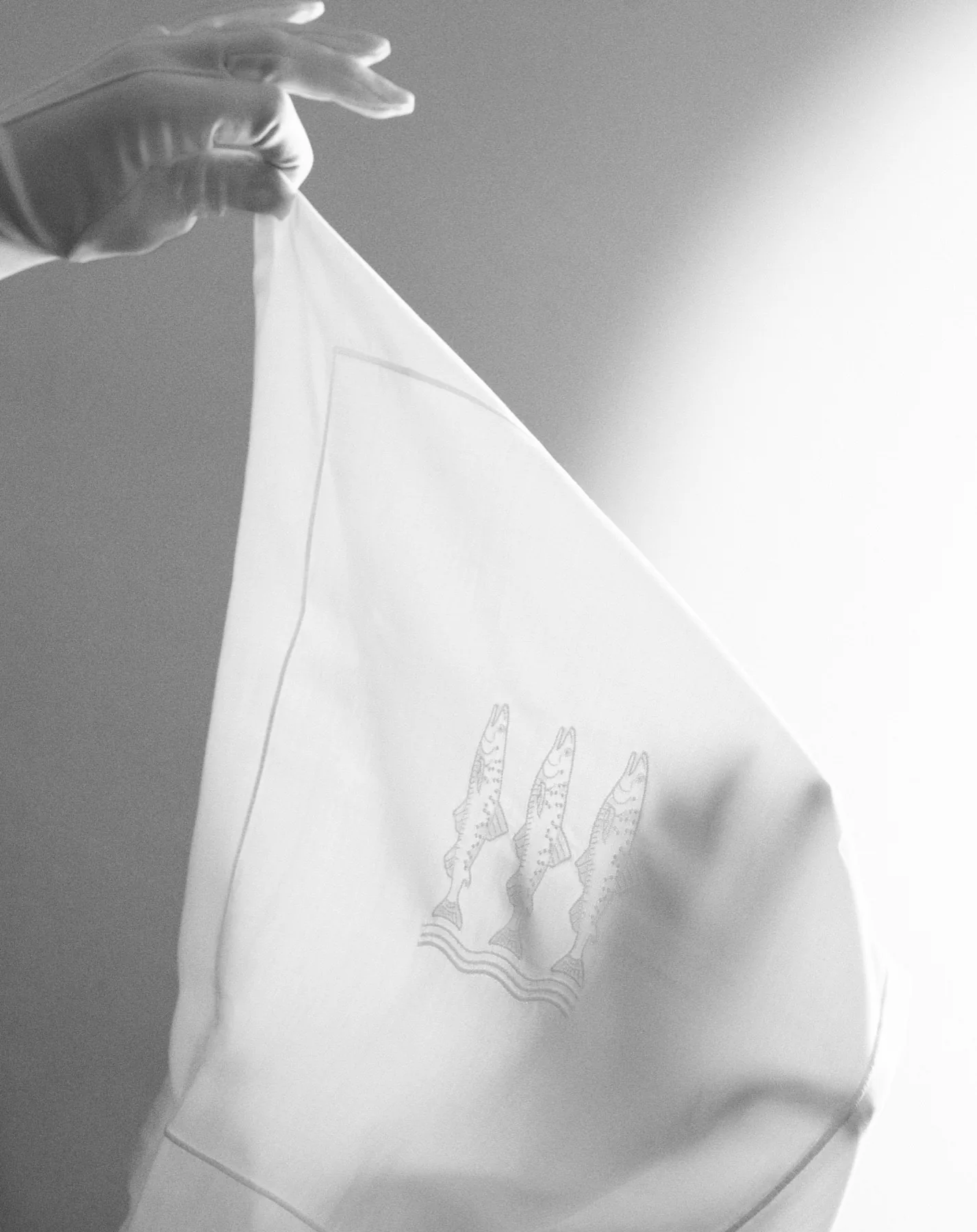 Gloved hands holding embroidered Beltrami linen made for Villa Passalacqua
