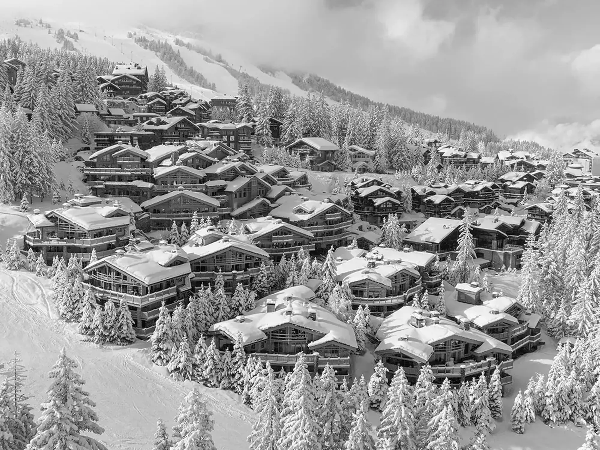 Snow-covered chalets and wooded slopes at Courchevel 1850